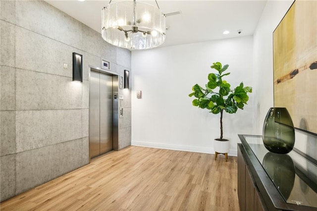 hall with an inviting chandelier, light hardwood / wood-style floors, and elevator