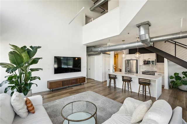 living room with a towering ceiling and dark hardwood / wood-style floors