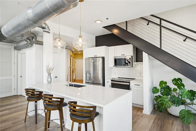 kitchen with stainless steel appliances, a kitchen bar, white cabinets, and sink