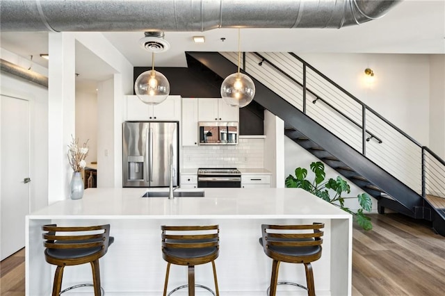 kitchen with white cabinets, backsplash, appliances with stainless steel finishes, and a breakfast bar