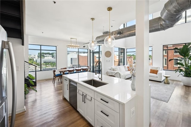 kitchen with white cabinetry, stainless steel appliances, an island with sink, sink, and hanging light fixtures