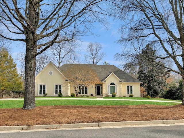 view of front of house with a front lawn, a shingled roof, and stucco siding