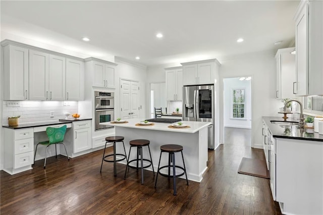 kitchen with appliances with stainless steel finishes, a kitchen island, a kitchen bar, and tasteful backsplash