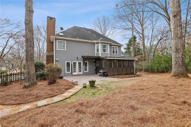 rear view of house featuring a patio area, a chimney, fence, and a sunroom