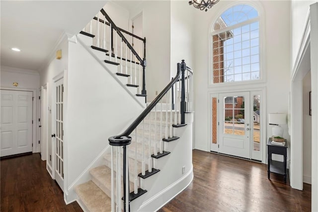 foyer featuring stairway, a high ceiling, ornamental molding, wood finished floors, and baseboards