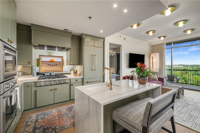2233 Peachtree Rd NE Unit 1207, Atlanta, GA 30309 - kitchen with green cabinets, a sink, stainless steel appliances, custom exhaust hood, and a breakfast bar area