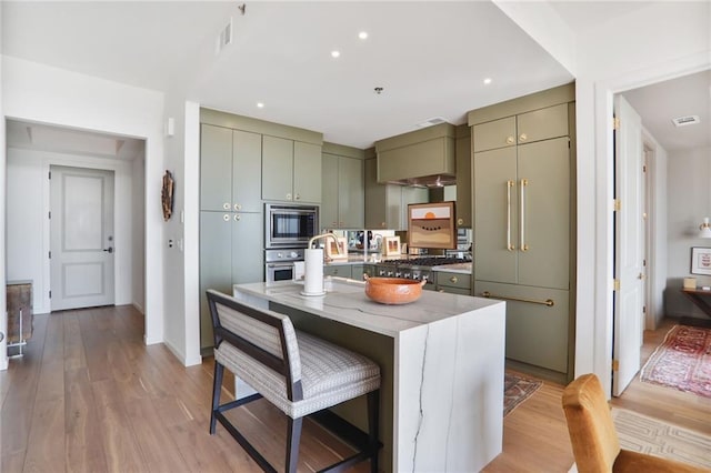 2233 Peachtree Rd NE Unit 1207, Atlanta, GA 30309 - kitchen featuring appliances with stainless steel finishes, light wood-style floors, a kitchen bar, light stone countertops, and a center island