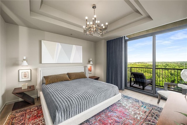 2233 Peachtree Rd NE Unit 1207, Atlanta, GA 30309 - bedroom with access to outside, wood finished floors, a chandelier, a tray ceiling, and a wall of windows
