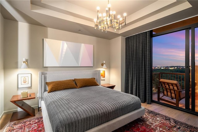 2233 Peachtree Rd NE Unit 1207, Atlanta, GA 30309 - bedroom featuring a raised ceiling, wood finished floors, a chandelier, and access to outside