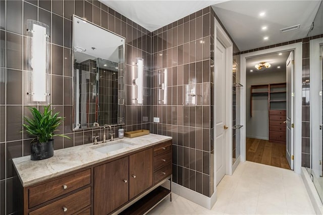 2233 Peachtree Rd NE Unit 1207, Atlanta, GA 30309 - bathroom with tile walls, a stall shower, a spacious closet, vanity, and tile patterned flooring