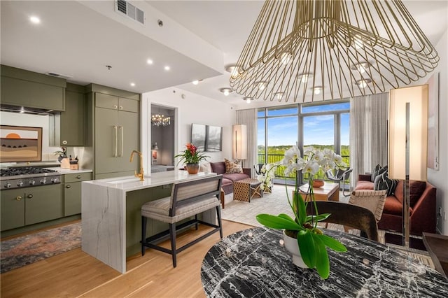 2233 Peachtree Rd NE Unit 1207, Atlanta, GA 30309 - kitchen featuring open floor plan, stainless steel gas stovetop, green cabinetry, a sink, and light wood finished floors