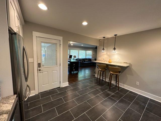 2314 Bryant Dr, Atlanta, GA 30344 - interior space featuring pendant lighting, white cabinetry, a breakfast bar area, stainless steel fridge, and light stone counters
