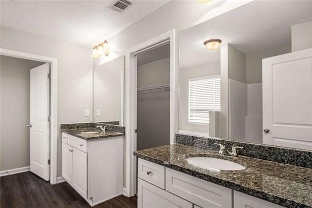 bathroom with visible vents, wood finished floors, a sink, and two vanities