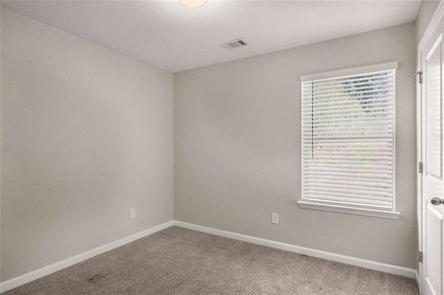 spare room with baseboards, carpet floors, visible vents, and plenty of natural light