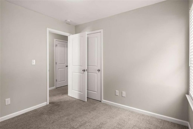 carpeted empty room featuring baseboards
