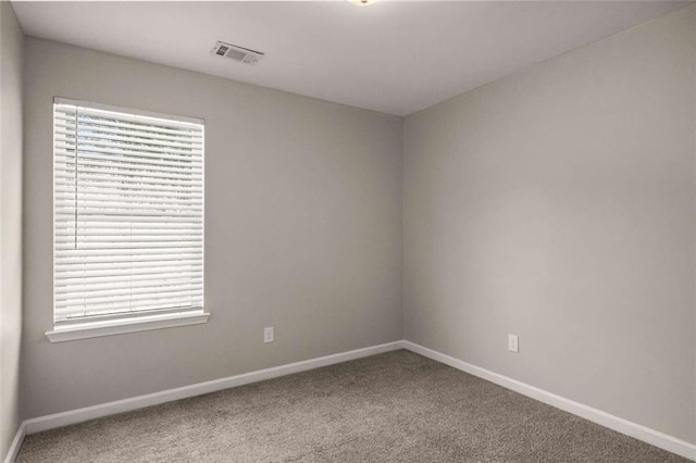 spare room with baseboards, visible vents, and carpet