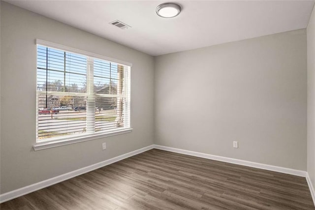unfurnished room with dark wood-type flooring, baseboards, and visible vents