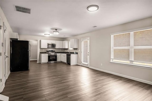 kitchen with white cabinetry, stainless steel appliances, dark wood-type flooring, dark countertops, and visible vents