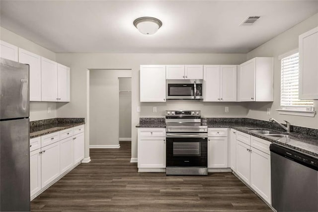 kitchen featuring dark wood-type flooring, white cabinets, a sink, and stainless steel appliances