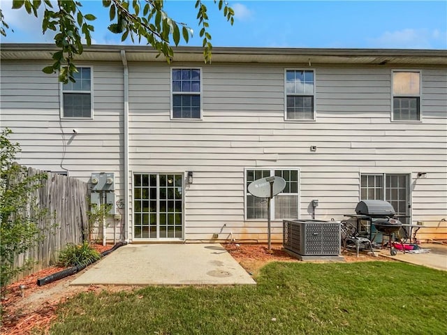 rear view of property featuring a lawn, central AC, and a patio area