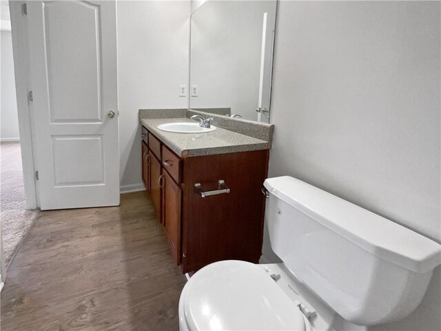 bathroom with toilet, hardwood / wood-style floors, and vanity