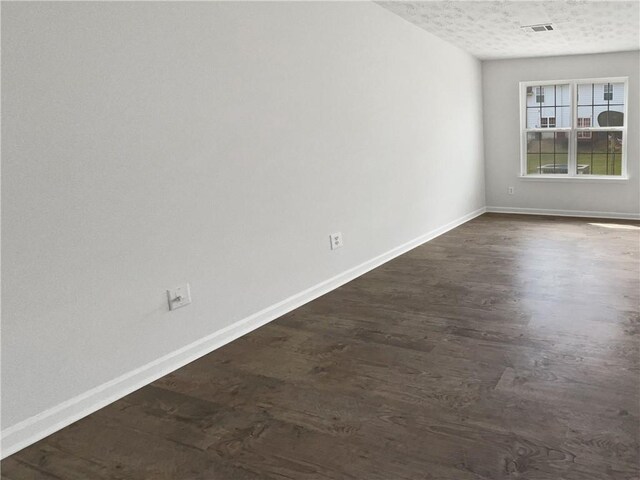 empty room with dark wood-type flooring and a textured ceiling