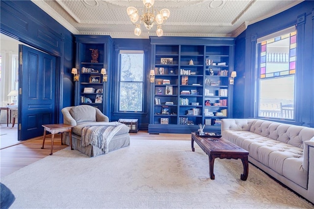 living room featuring an ornate ceiling, built in features, a wealth of natural light, and a chandelier