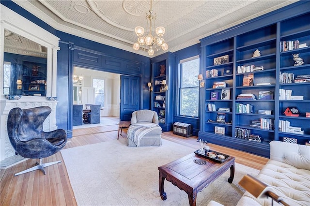 living room with built in features, wood finished floors, a notable chandelier, and an ornate ceiling