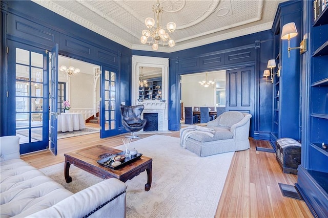 living area with a tray ceiling, light wood-type flooring, a notable chandelier, and stairway