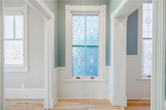 entryway with wood finished floors, wainscoting, and a wealth of natural light