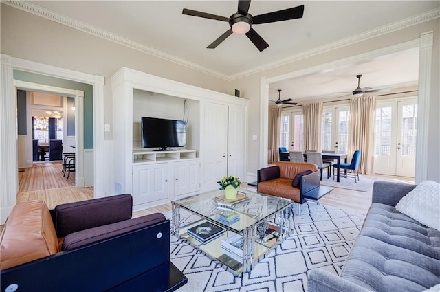 living room featuring light wood-type flooring, ornamental molding, a wainscoted wall, and ceiling fan
