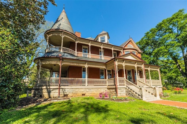 victorian home featuring covered porch, a front yard, and a balcony