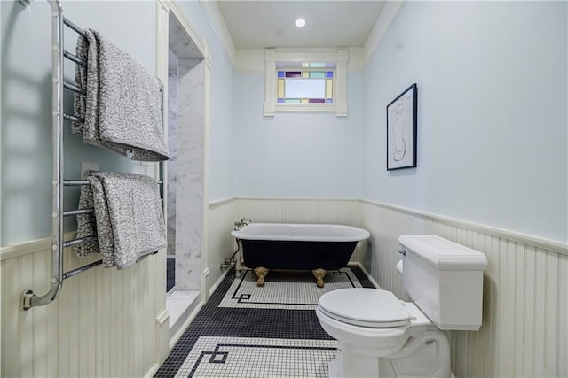 full bathroom with toilet, a soaking tub, a shower stall, and a wainscoted wall