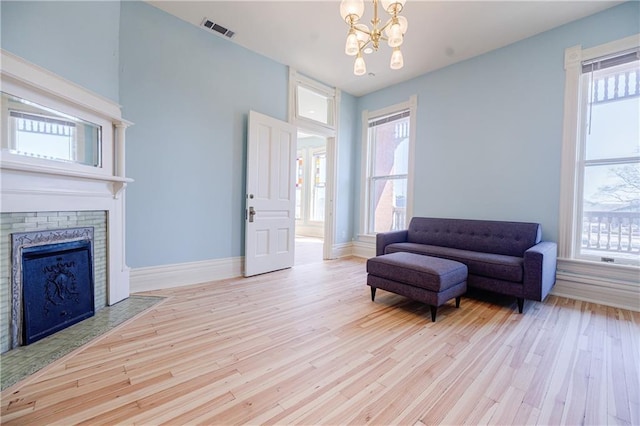 living area featuring visible vents, an inviting chandelier, wood finished floors, and a healthy amount of sunlight