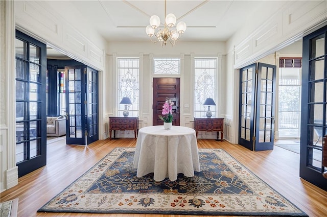 dining area with light wood-style floors, a notable chandelier, french doors, and visible vents
