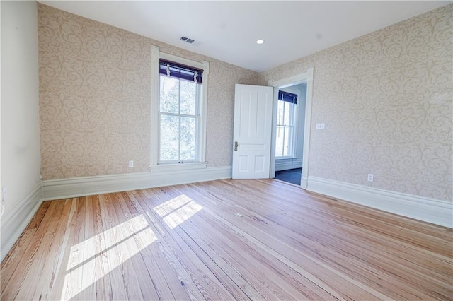 unfurnished room with visible vents, baseboards, wood finished floors, and wallpapered walls