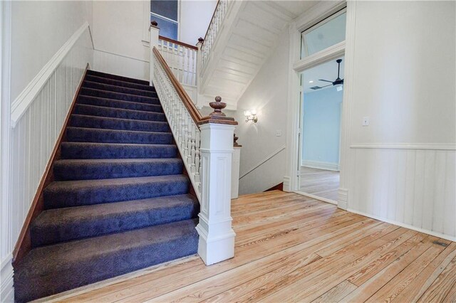 stairs with wood finished floors and a ceiling fan