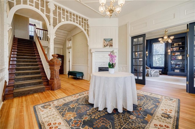 dining area featuring a chandelier, arched walkways, wainscoting, hardwood / wood-style floors, and a decorative wall
