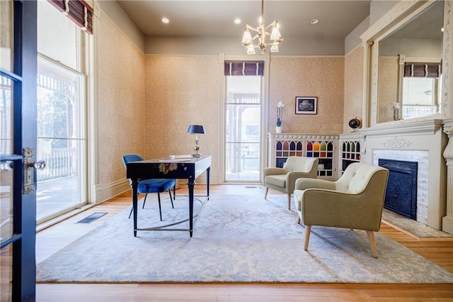 office featuring wallpapered walls, visible vents, an inviting chandelier, and wood finished floors