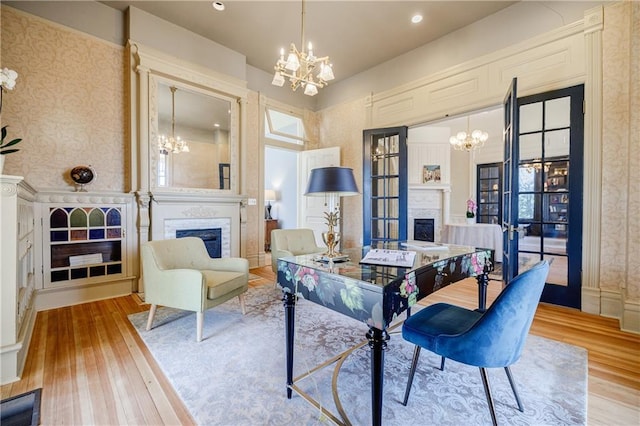 dining room featuring wallpapered walls, a notable chandelier, wood finished floors, and a fireplace