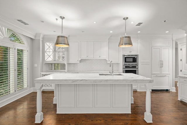 kitchen featuring pendant lighting, sink, stainless steel appliances, an island with sink, and white cabinets