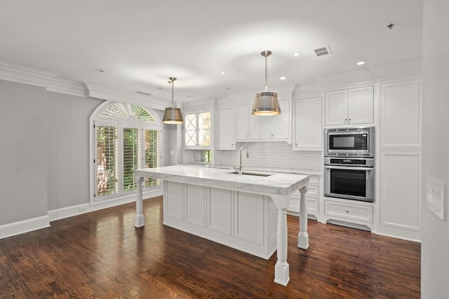 kitchen featuring sink, white cabinetry, hanging light fixtures, stainless steel appliances, and an island with sink