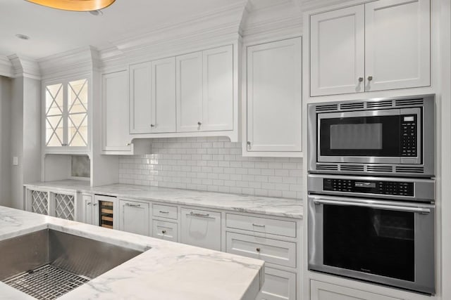 kitchen featuring white cabinetry, appliances with stainless steel finishes, light stone counters, and backsplash