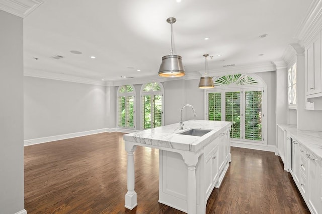 kitchen with sink, white cabinetry, light stone counters, a center island with sink, and decorative light fixtures