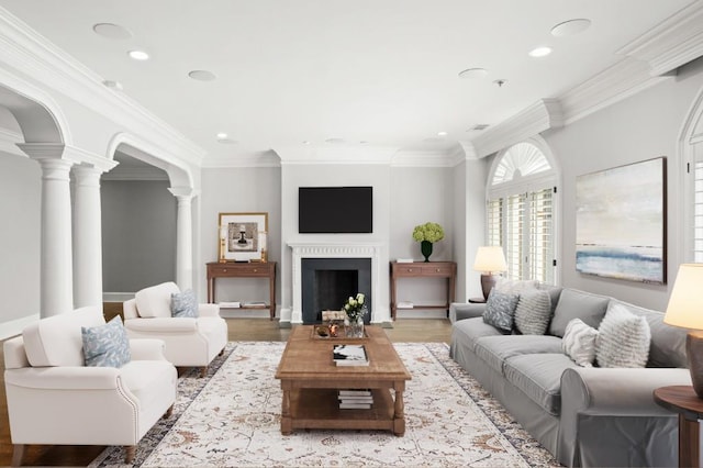 living room featuring crown molding, light hardwood / wood-style floors, and decorative columns