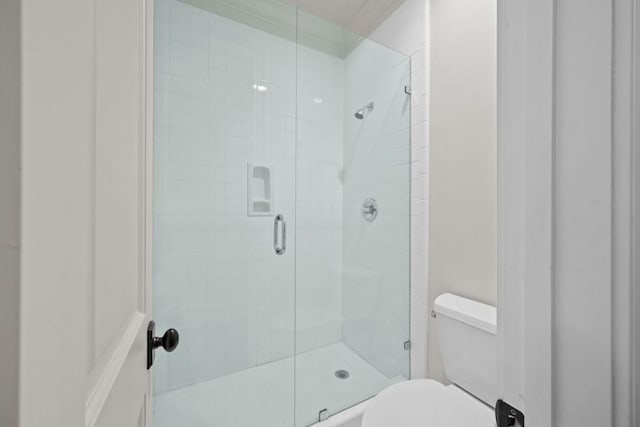 bathroom featuring a shower with shower door and toilet