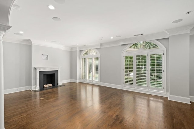 unfurnished living room featuring decorative columns, crown molding, and dark hardwood / wood-style floors