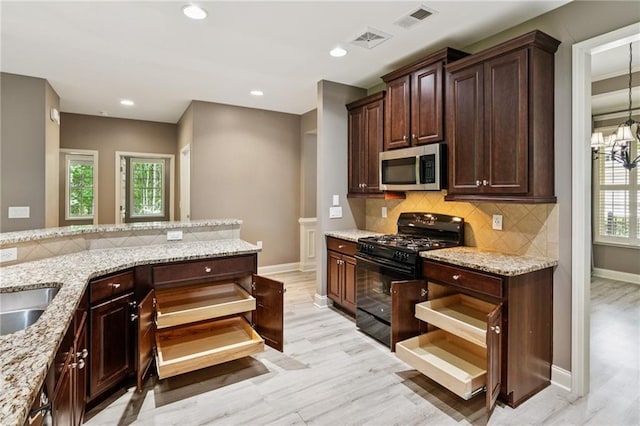 328 Shade Tree Cir, Woodstock, GA 30188 - kitchen with stainless steel microwave, black range with gas cooktop, light wood-style flooring, decorative backsplash, and recessed lighting