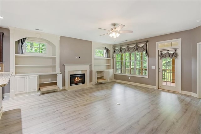 328 Shade Tree Cir, Woodstock, GA 30188 - unfurnished living room featuring ceiling fan, light wood-type flooring, a glass covered fireplace, and built in features