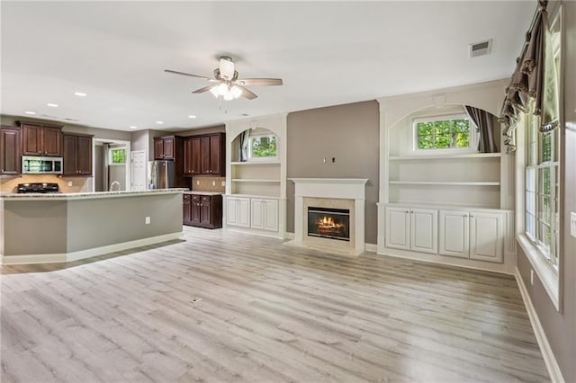 328 Shade Tree Cir, Woodstock, GA 30188 - kitchen featuring stainless steel appliances, light wood finished floors, light countertops, recessed lighting, and a fireplace with flush hearth